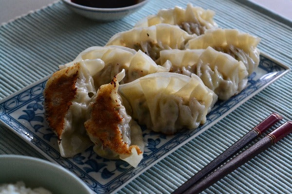 Gyoza on a Japanese serving dish with chopsticks
